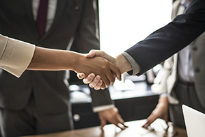 Close-up of professionals shaking hands across a conference table following a legal settlement or mediation.